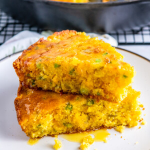 slices of cheesy jiffy cornbread stacked on a white plate