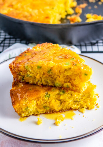 slices of cheesy jiffy cornbread stacked on a white plate