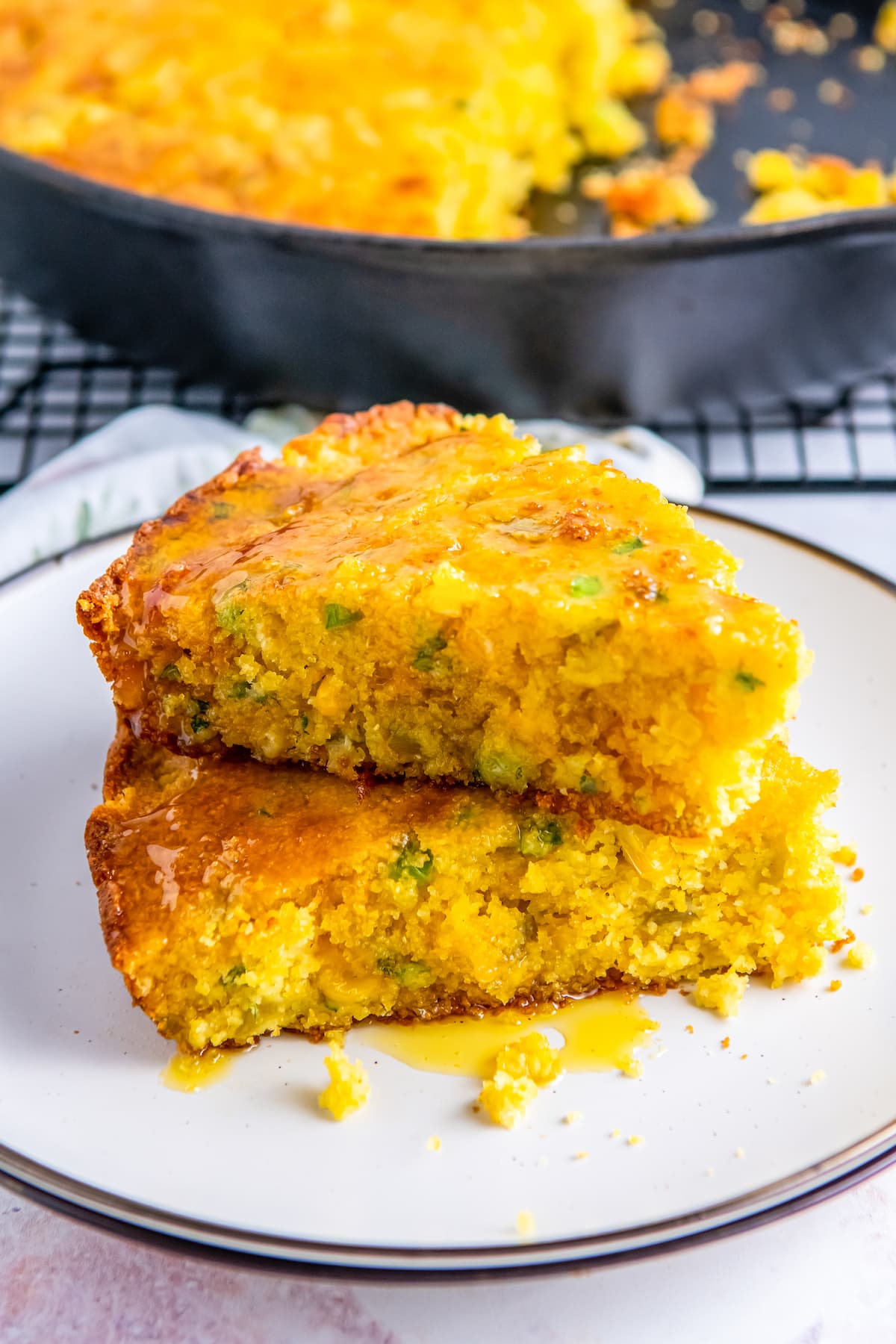 slices of cheesy jiffy cornbread stacked on a white plate