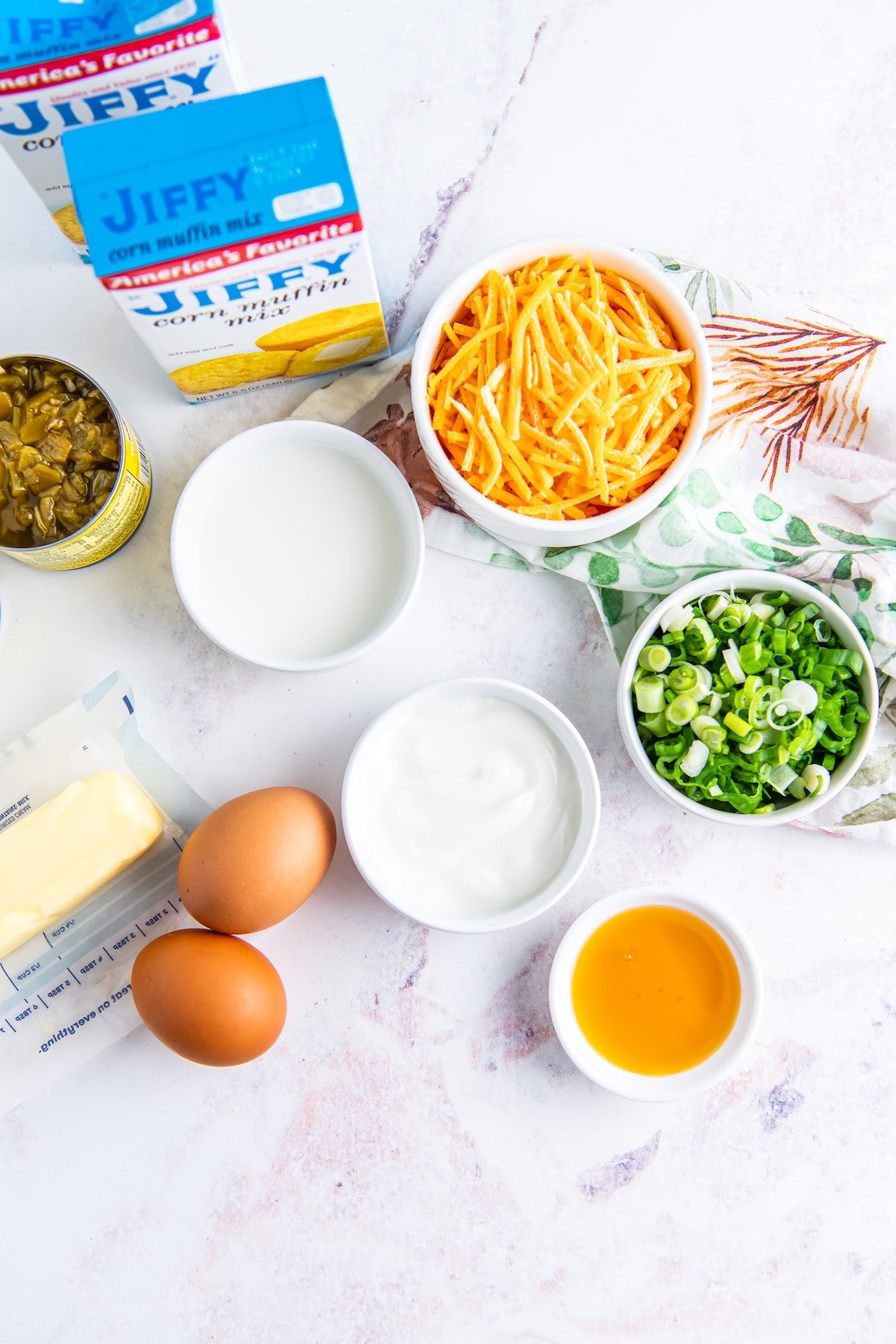 ingredients to make cheesy jiffy cornbread like the box mix, cheese, eggs, green chilis, butter, and sliced green onions