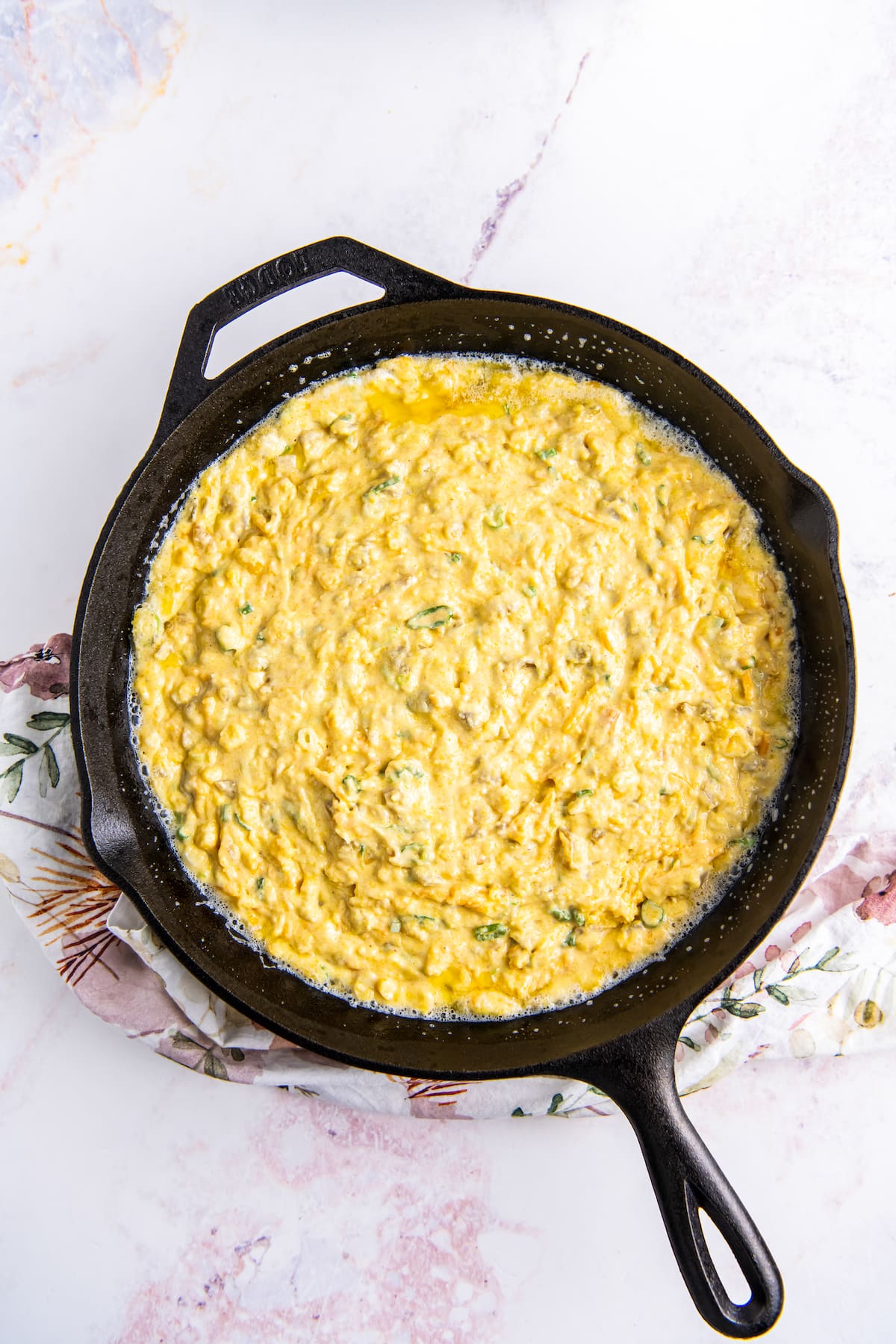 cheesy jiffy cornbread batter in a cast iron skillet