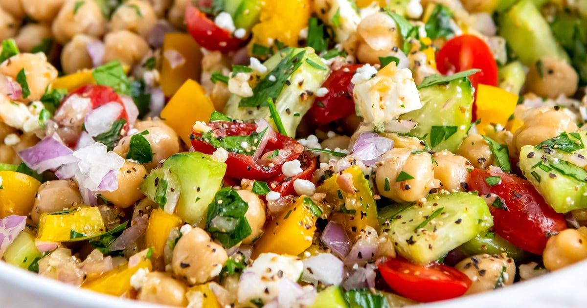 close up of a salad made with chickpeas, feta, cucumbers, herbs, tomatoes, and red onions