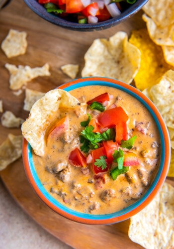 a bowl of chili con queso with a side of chips