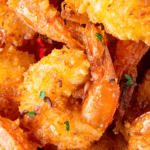 Coconut shrimp stacked on top of each other with parsley on top.