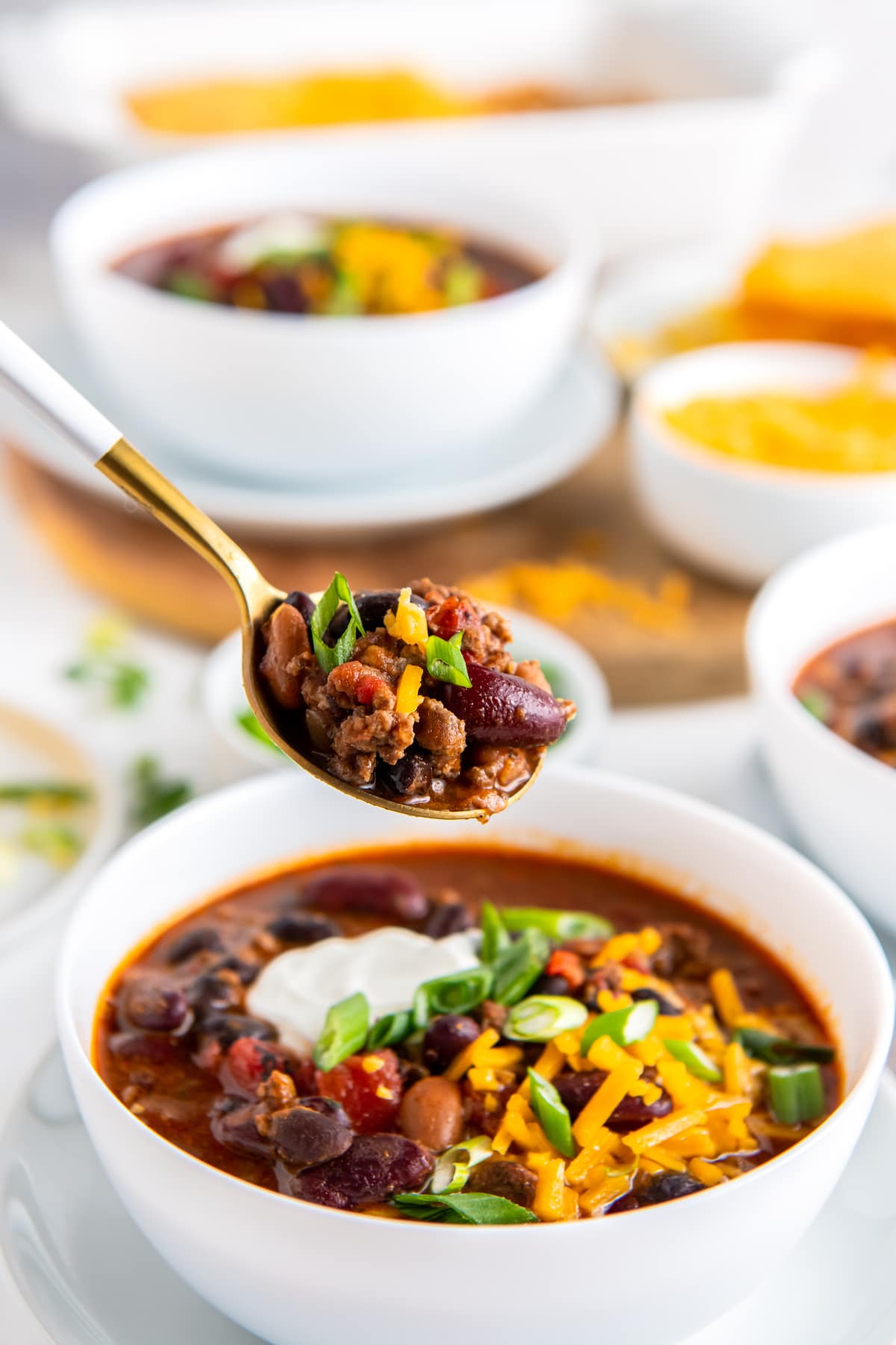 a spoon taking a bite out of a bowl of chili