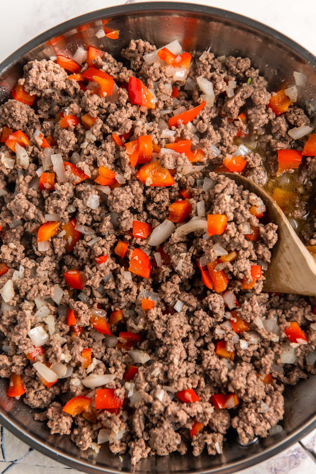 ground beef being cooked in a pan with peppers and onions