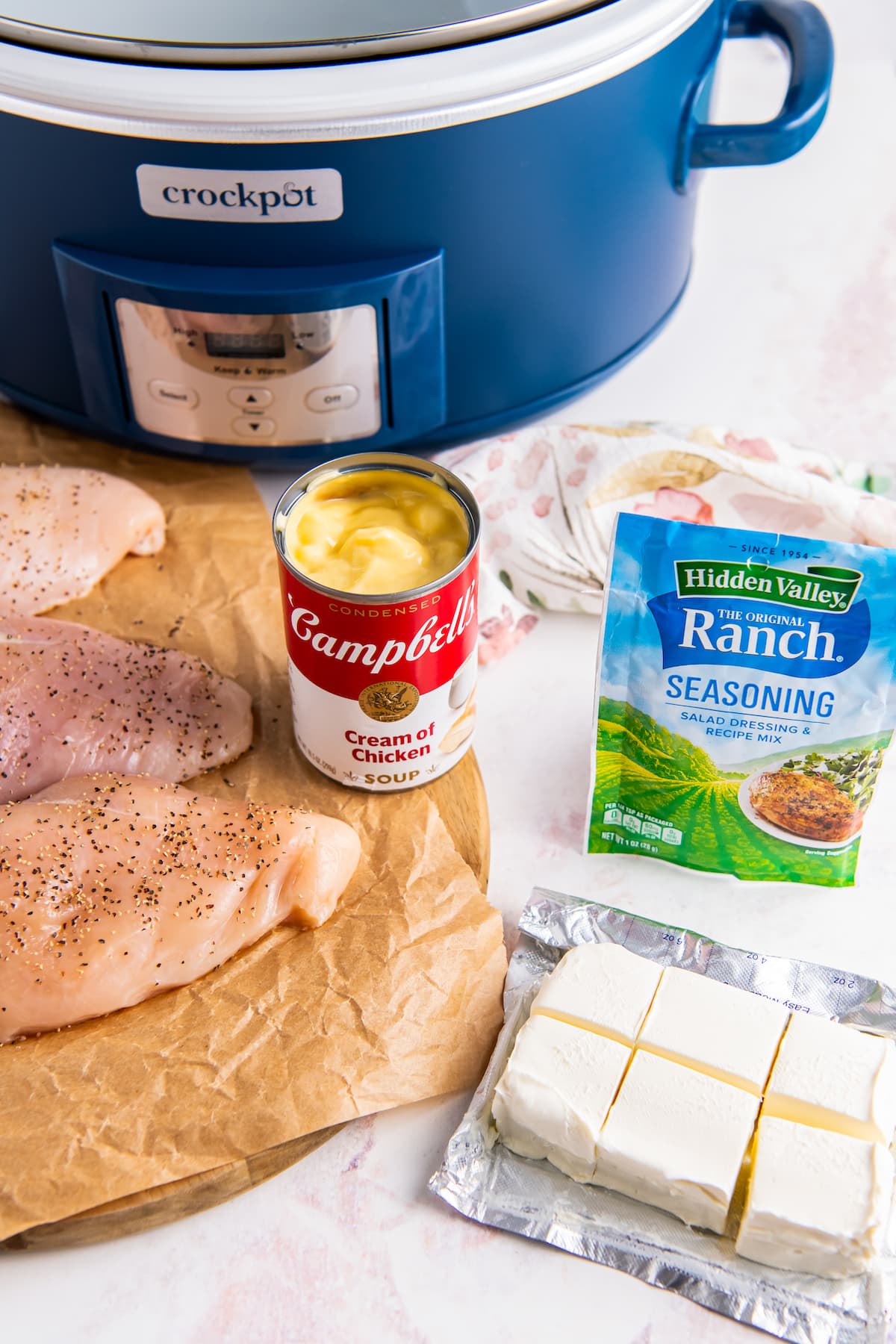 a crockpot, can of soup, chicken breasts, and ranch seasoning packet