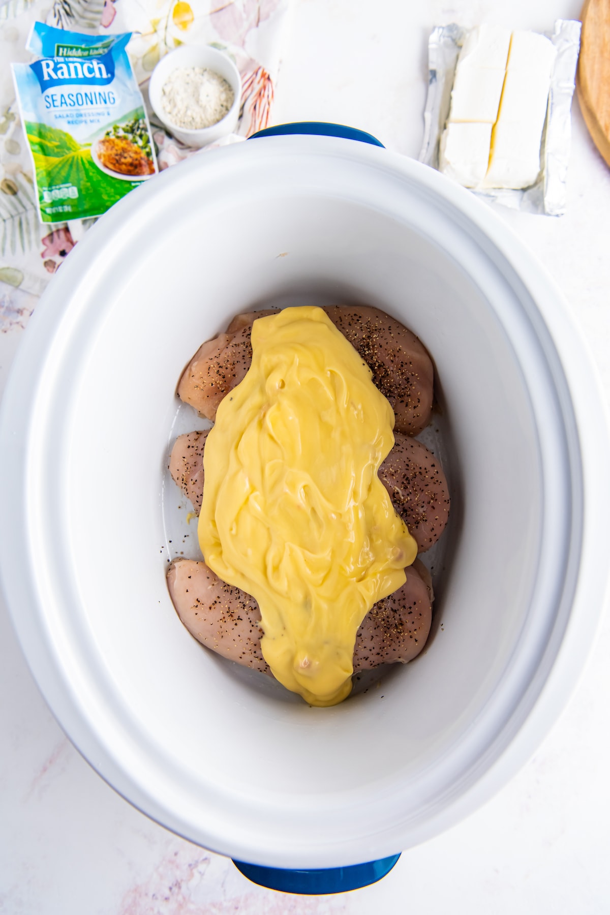 three chicken breasts in a crockpot with cream of chicken soup poured on top