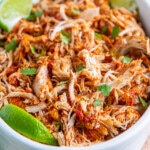 a casserole dish with shredded chicken tossed in salsa and fresh herbs