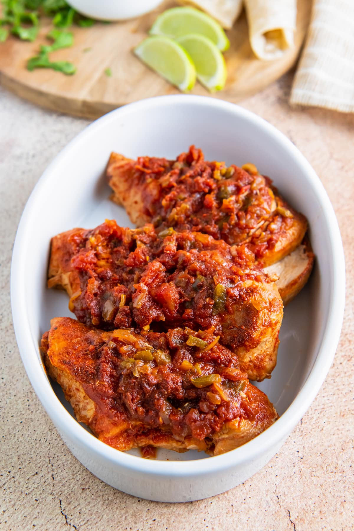 three chicken breasts in a casserole dish smothered in salsa