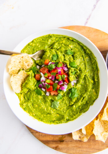 a bowl of guacamole with two tortilla chips dipped into it