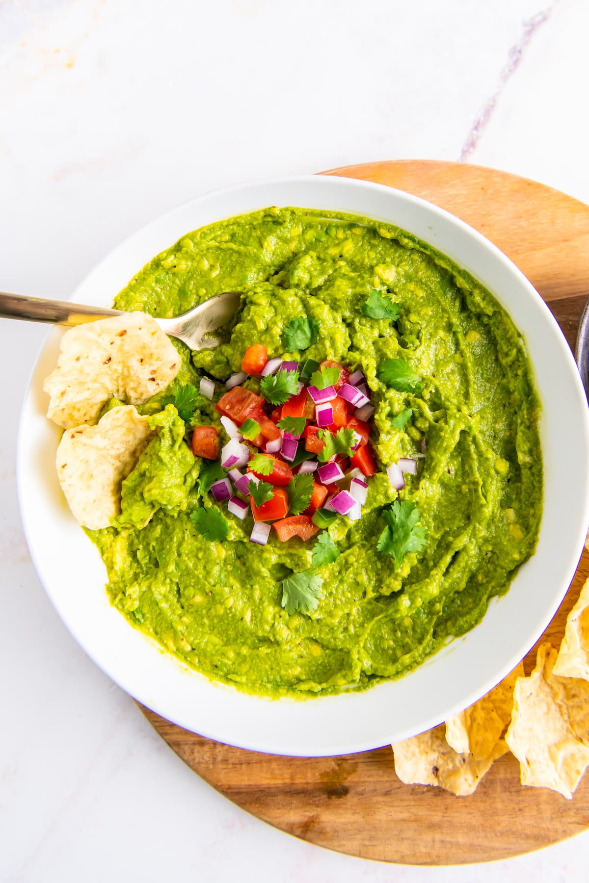 a bowl of guacamole with two tortilla chips dipped into it