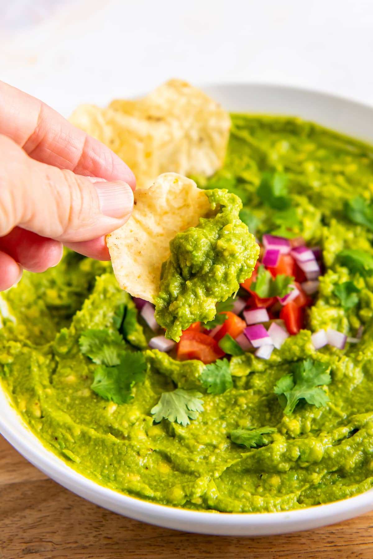 someone dipping a tortilla chip into a bowl of guacamole