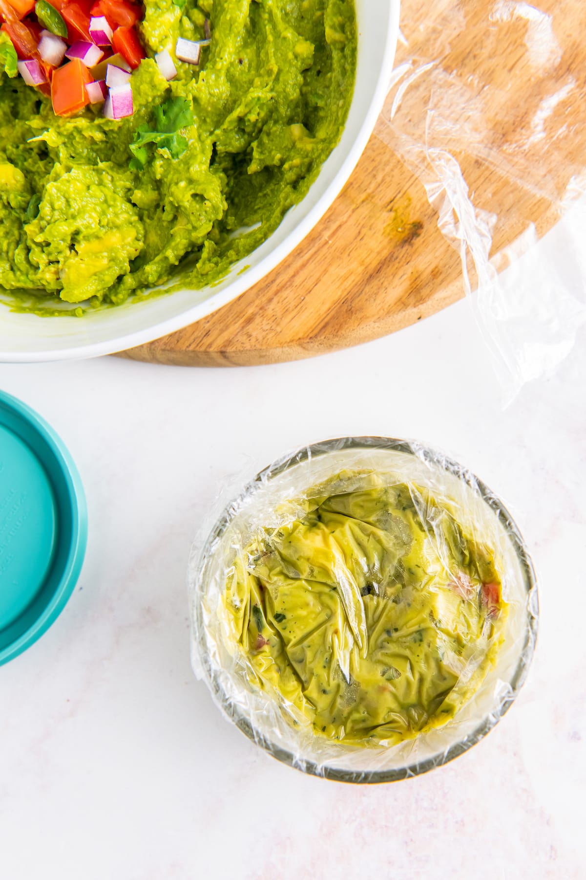 guacamole being covered with plastic wrap in a small bowl
