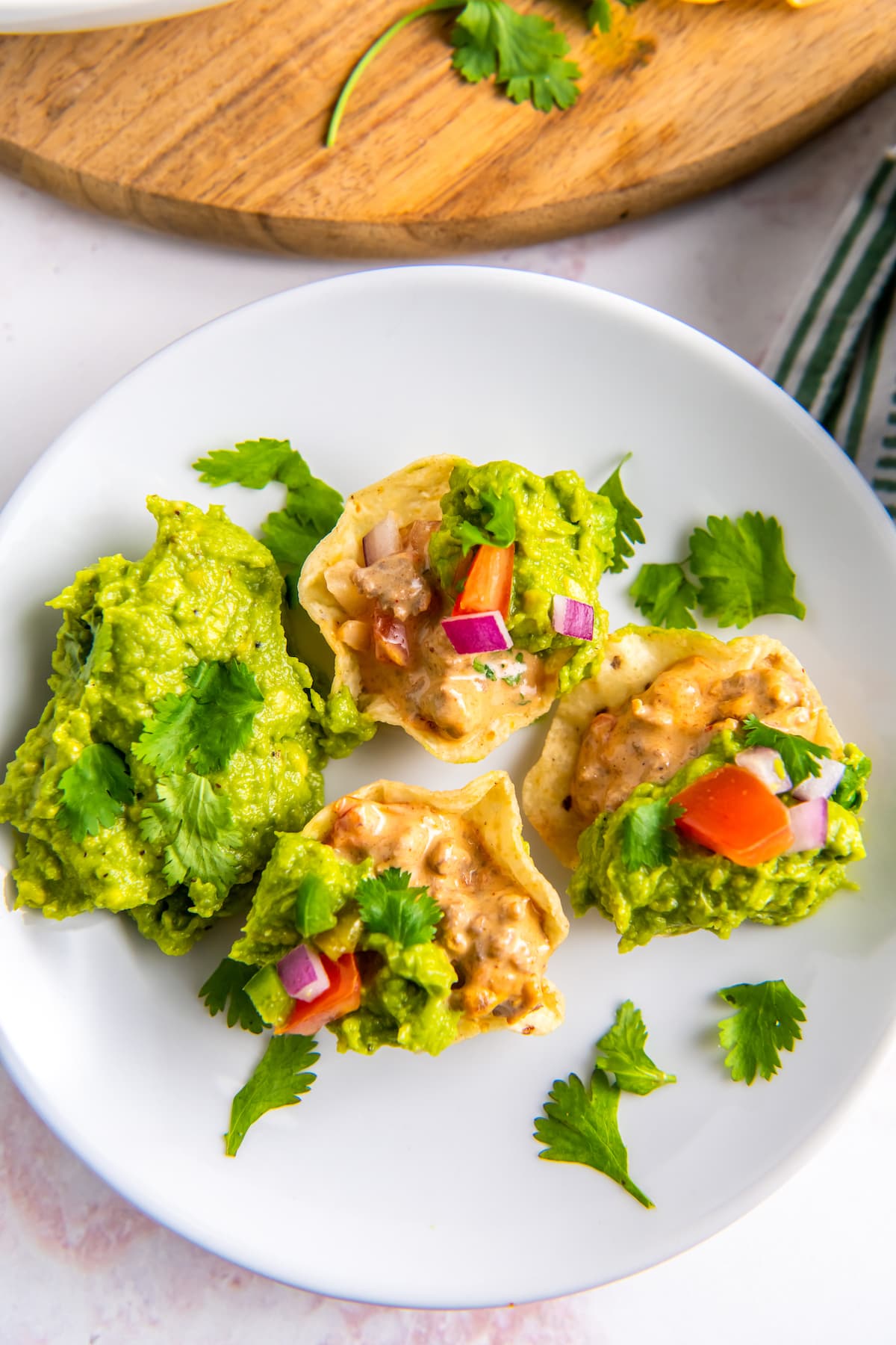 a plate with tortilla chips each with a scoop of guacamole and a dollop of guacamole on the side