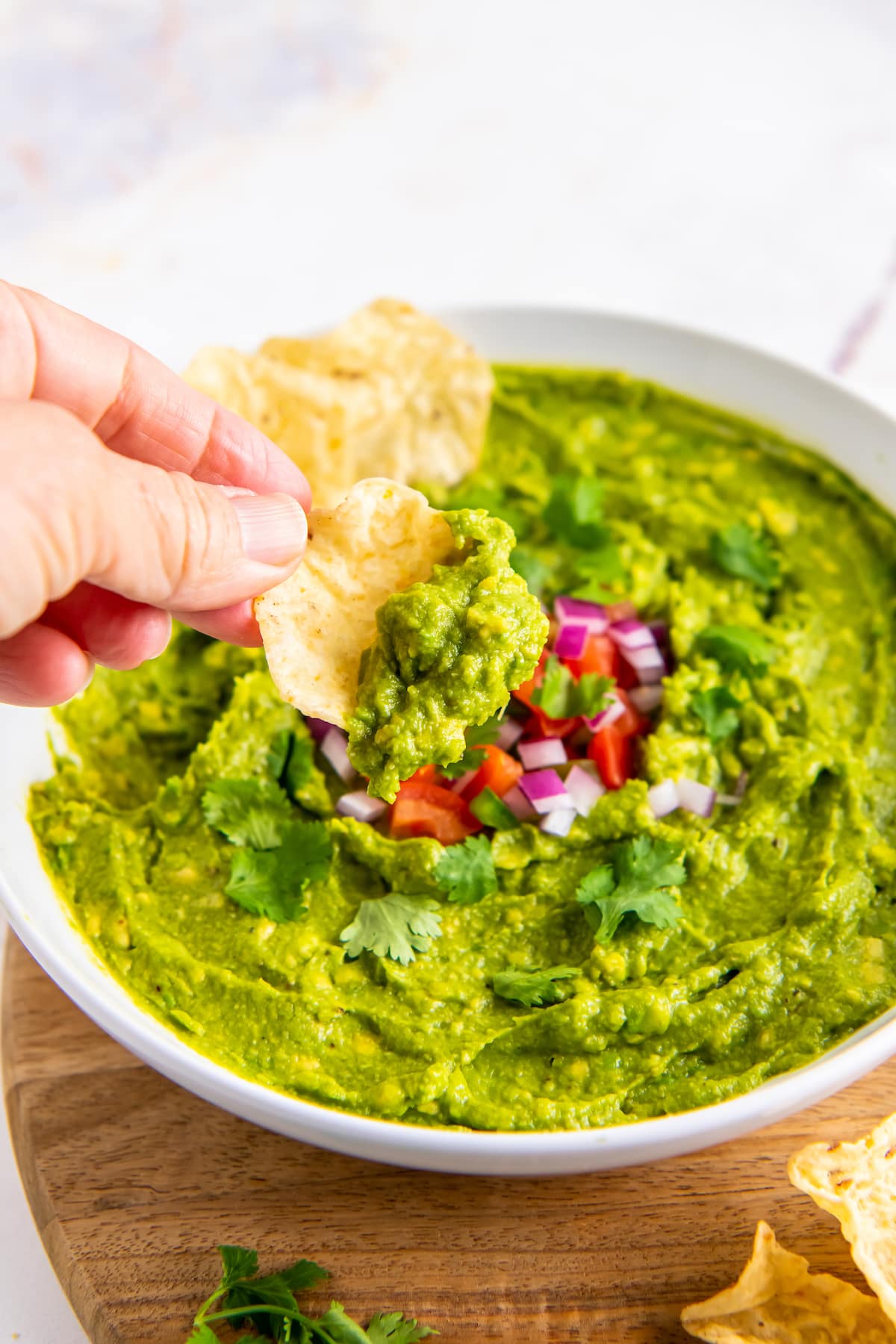 someone dipping a tortilla chip into a bowl of guacamole
