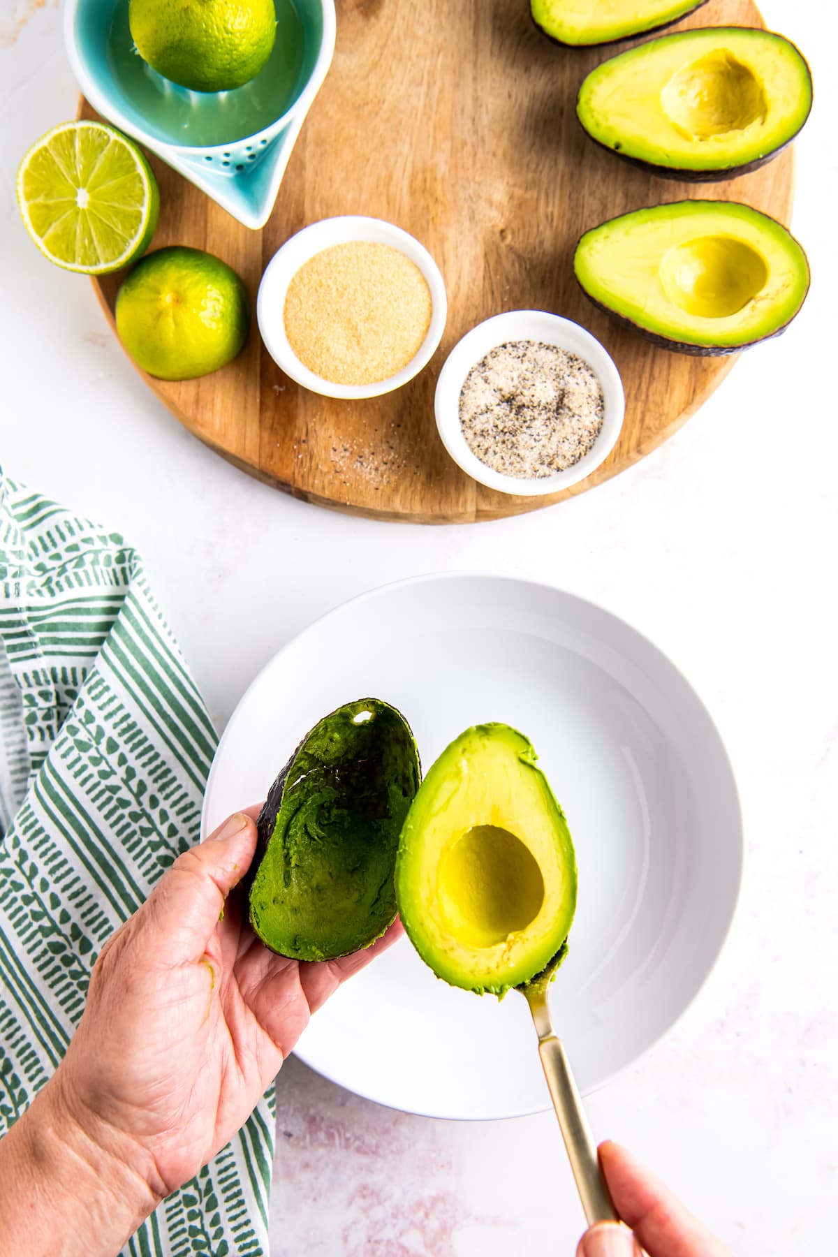 hands scooping avocado and placing it into a bowl