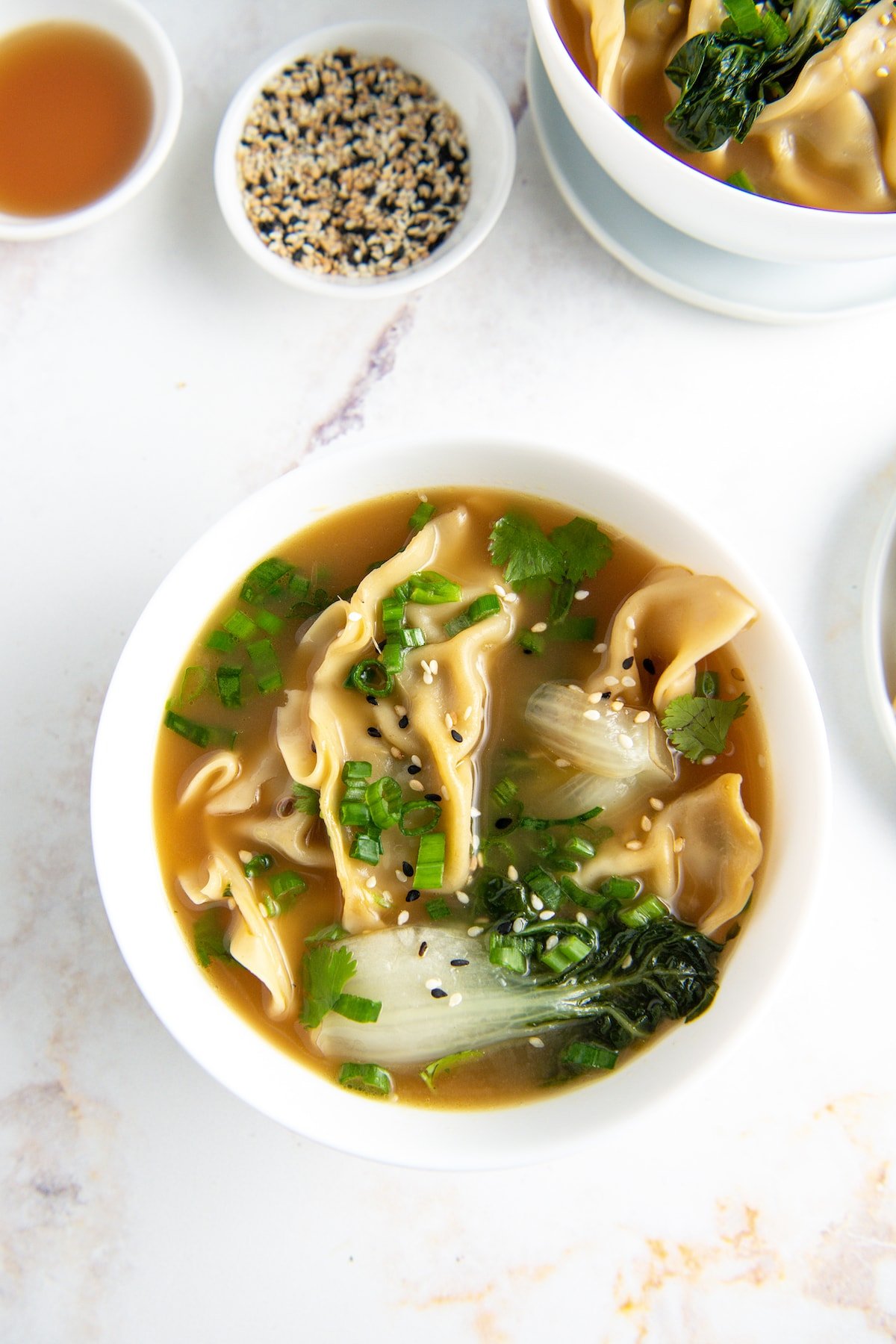potsticker soup with herbs and bok choy in a white bowl