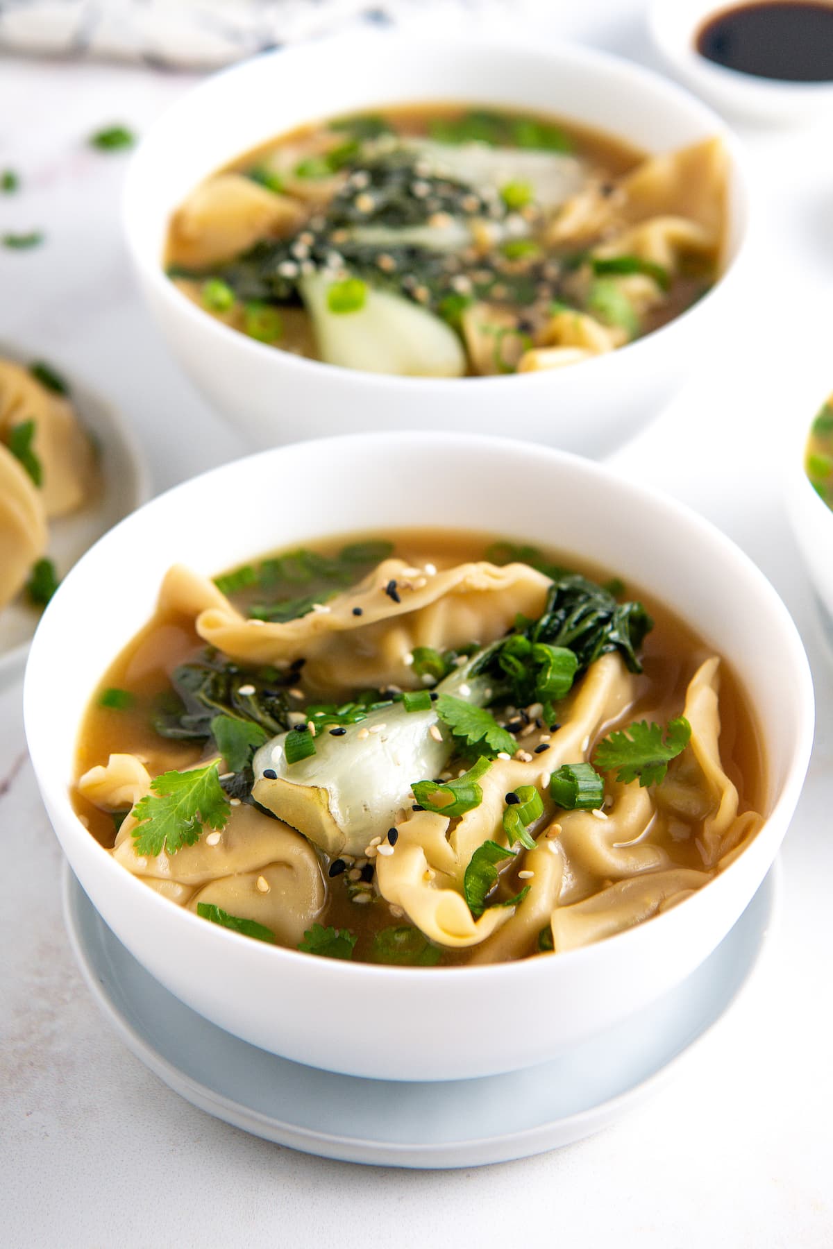 potsticker soup with herbs and bok choy in a white bowl