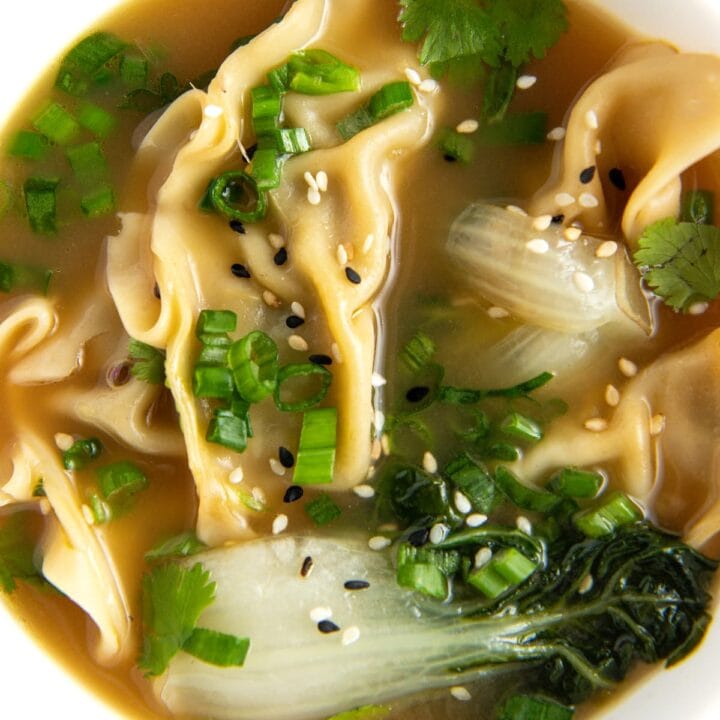 potsticker soup with herbs and bok choy in a white bowl