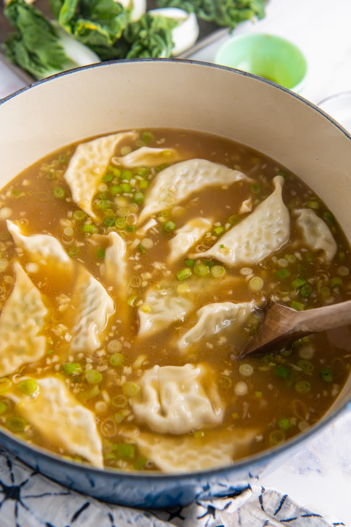 frozen dumplings floating in broth in a large pot