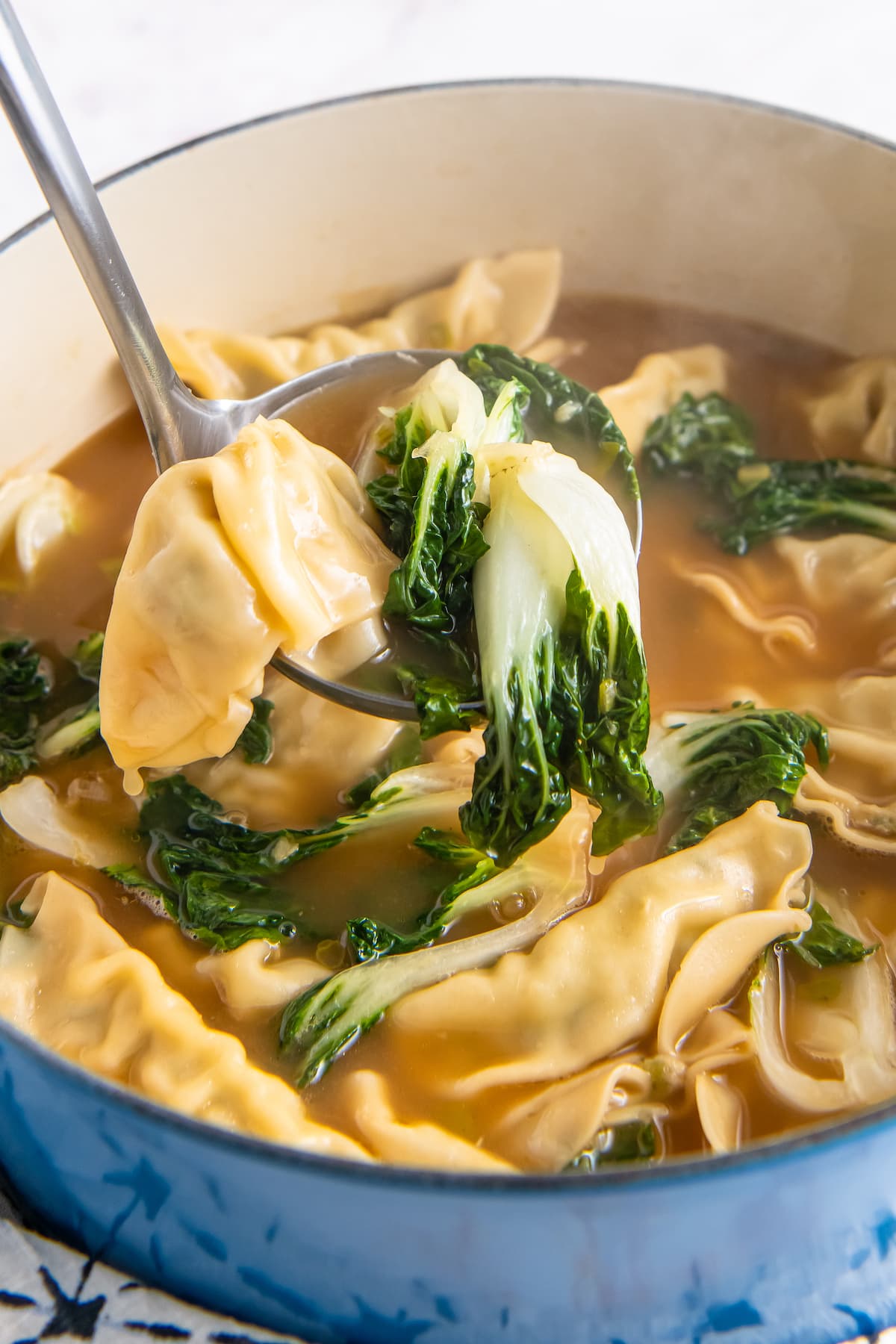 cooked dumplings in broth with greens in a large pot making potsticker soup