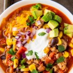 Taco soup in a bowl with all the toppings.