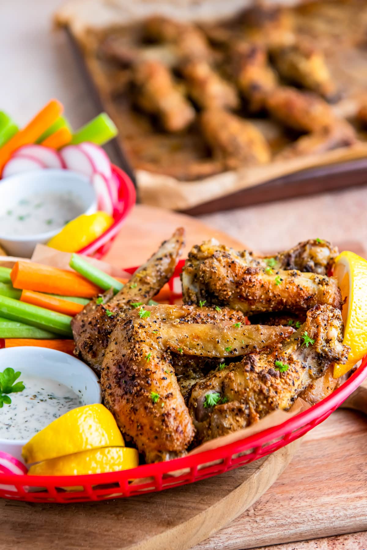 a plate of lemon pepper chicken wings with vegetables on the side and dipping sauce