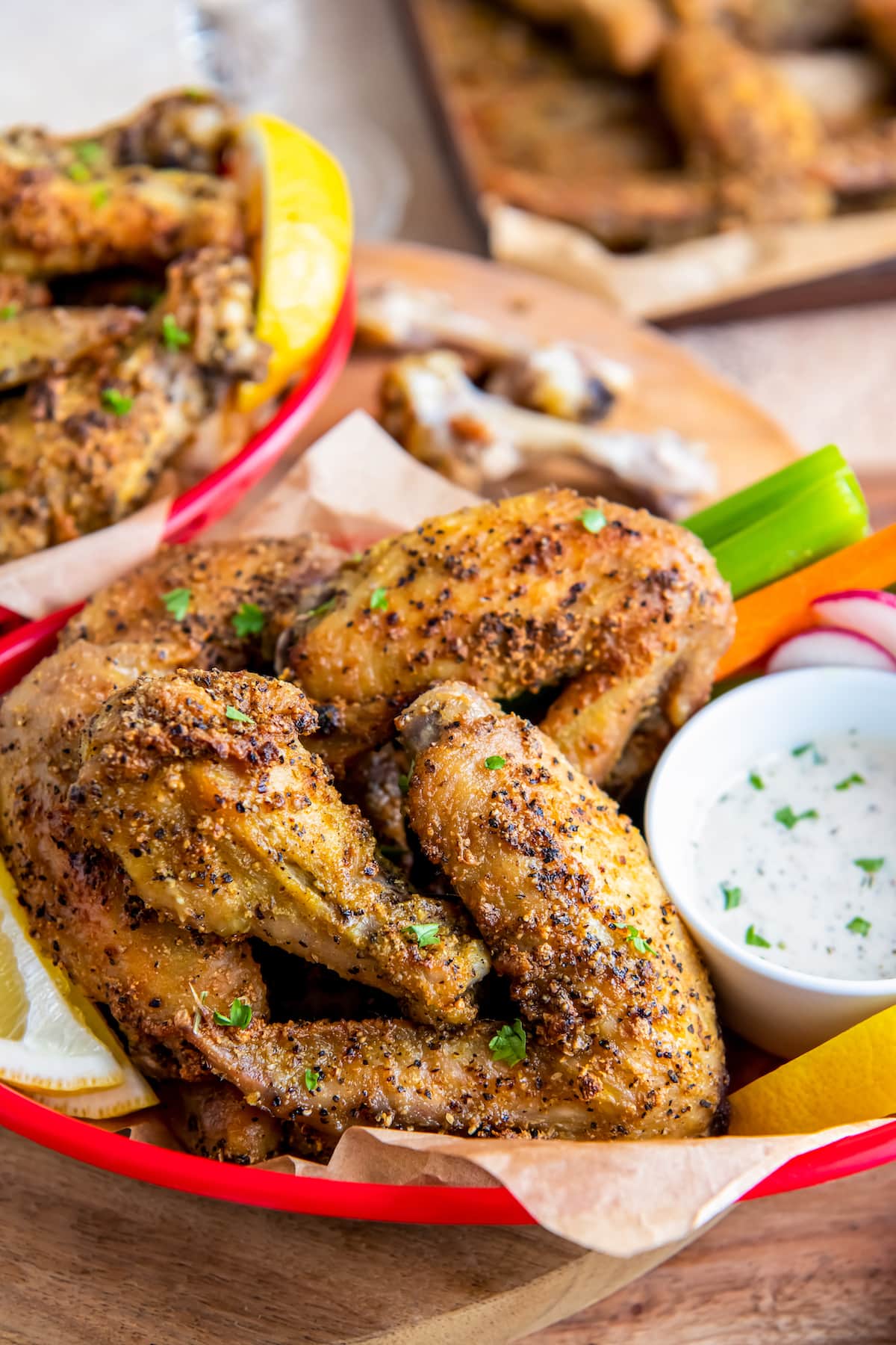 a plate of lemon pepper chicken wings with vegetables on the side and dipping sauce