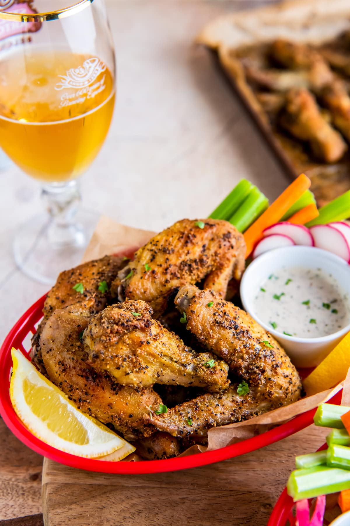 a plate of lemon pepper chicken wings with vegetables on the side and dipping sauce