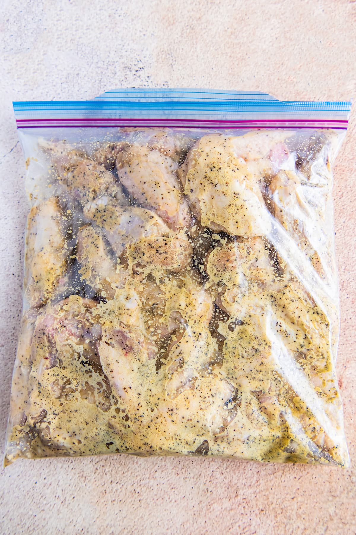 a large ziplock bag with chicken wings and seasoning