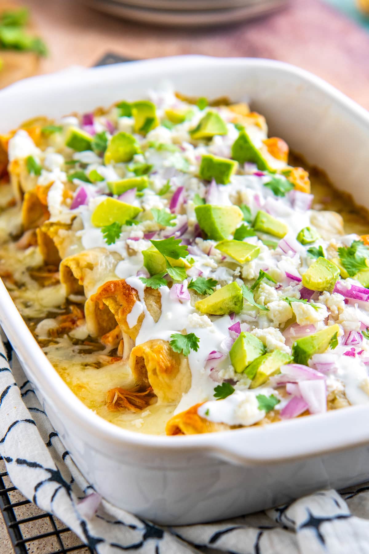 casserole dish with baked salsa verde chicken enchiladas and various toppings