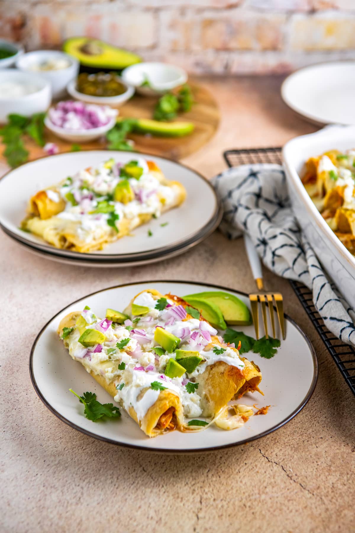 two plates with two enchiladas on each plate