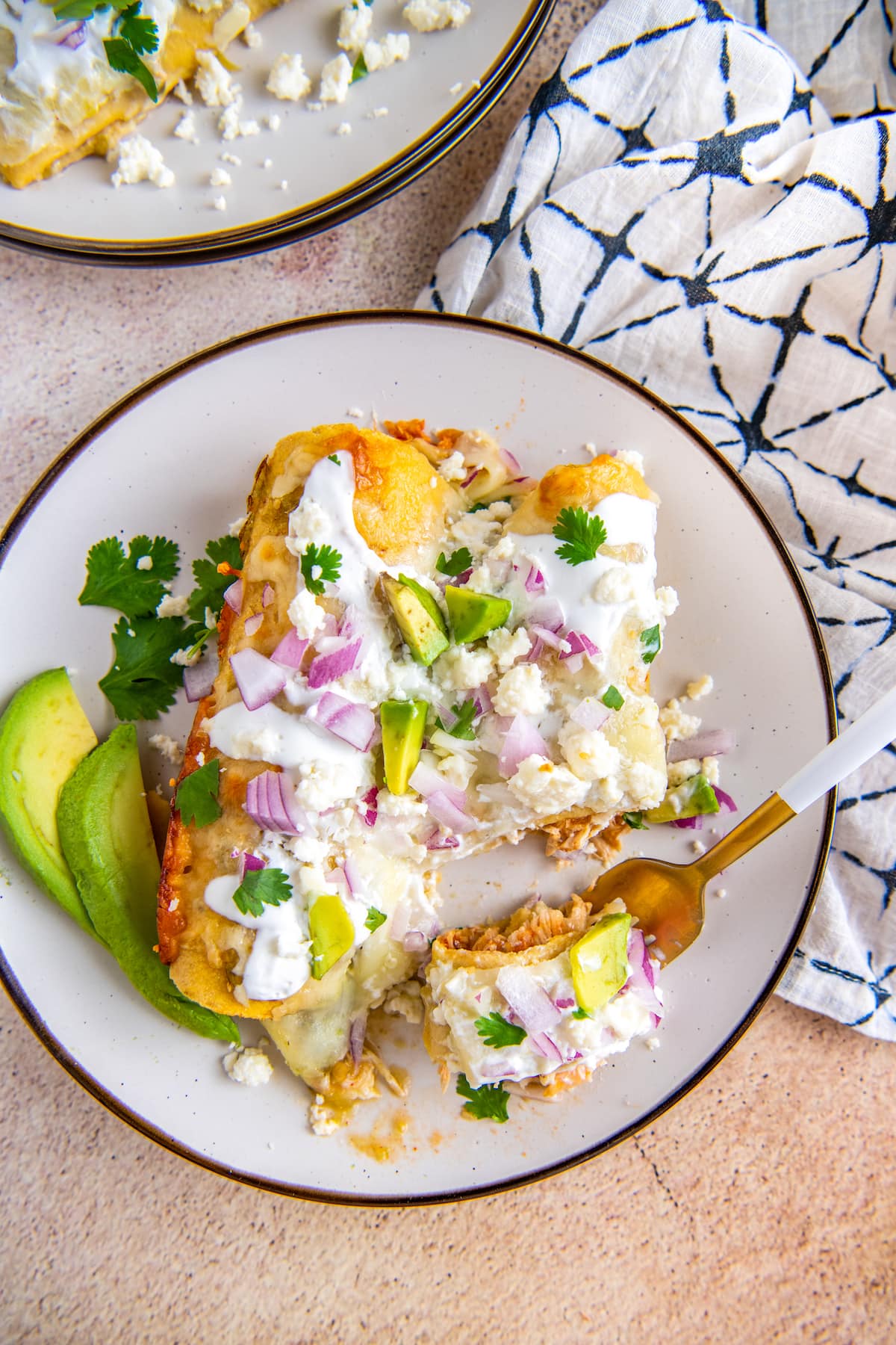 a fork that has cut into two enchiladas on a plate