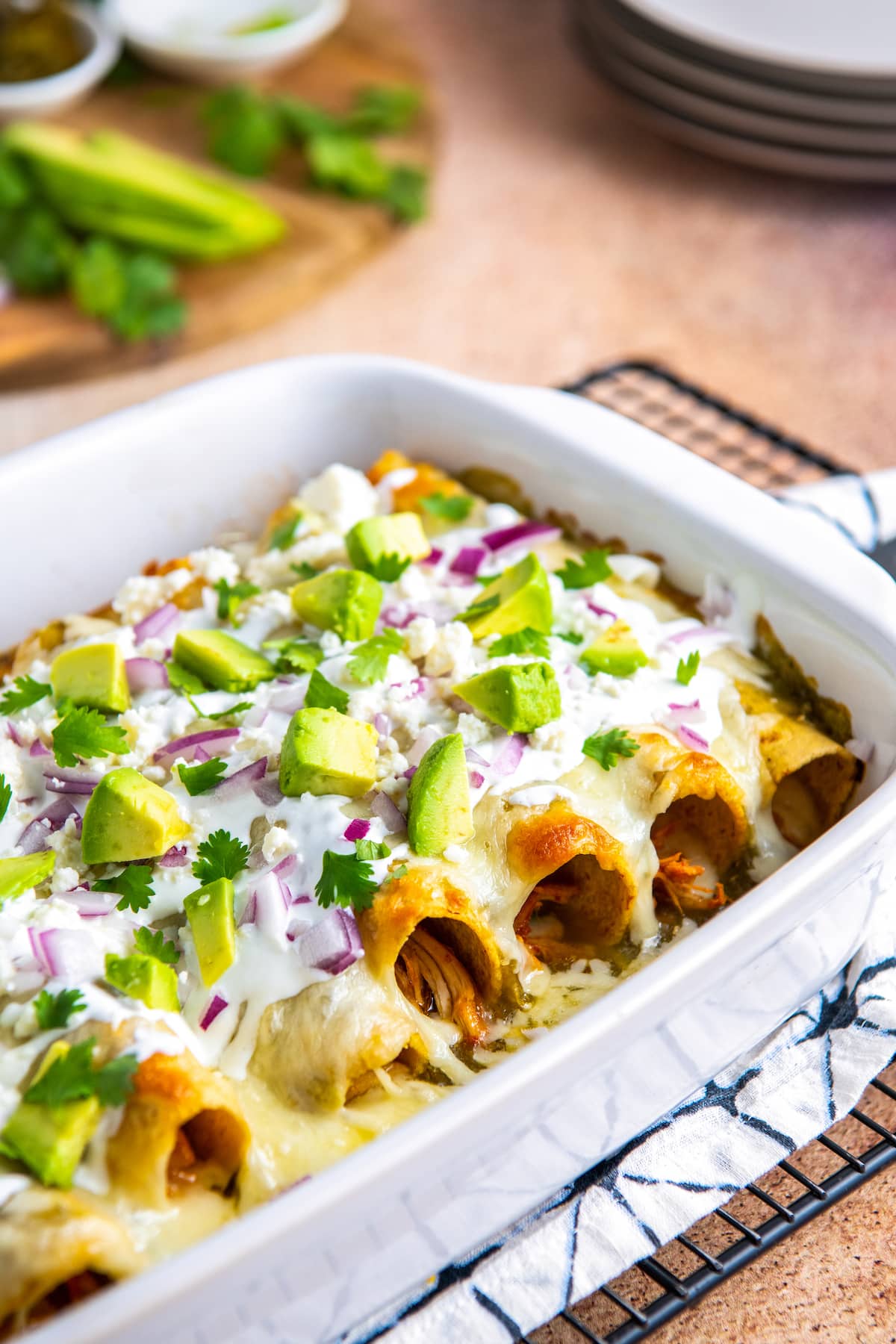 casserole dish with baked salsa verde chicken enchiladas and various toppings