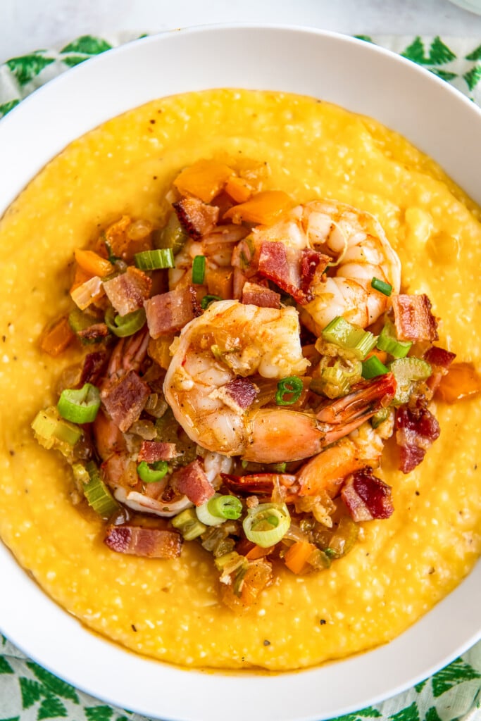 a bowl of shrimp and grits on a green and white napkin