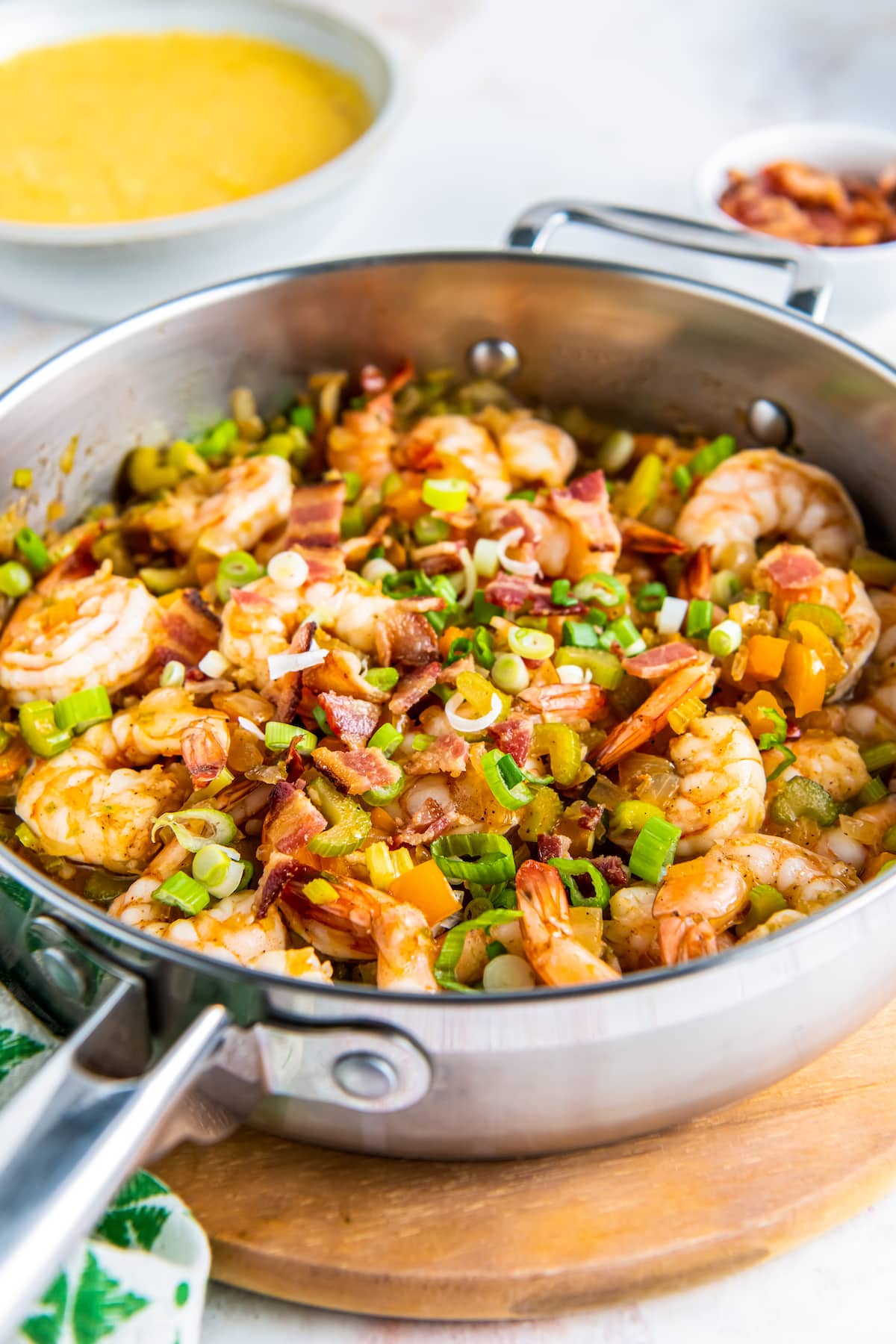 a pan with cooked shrimp with sliced green onions, bacon, and bell peppers