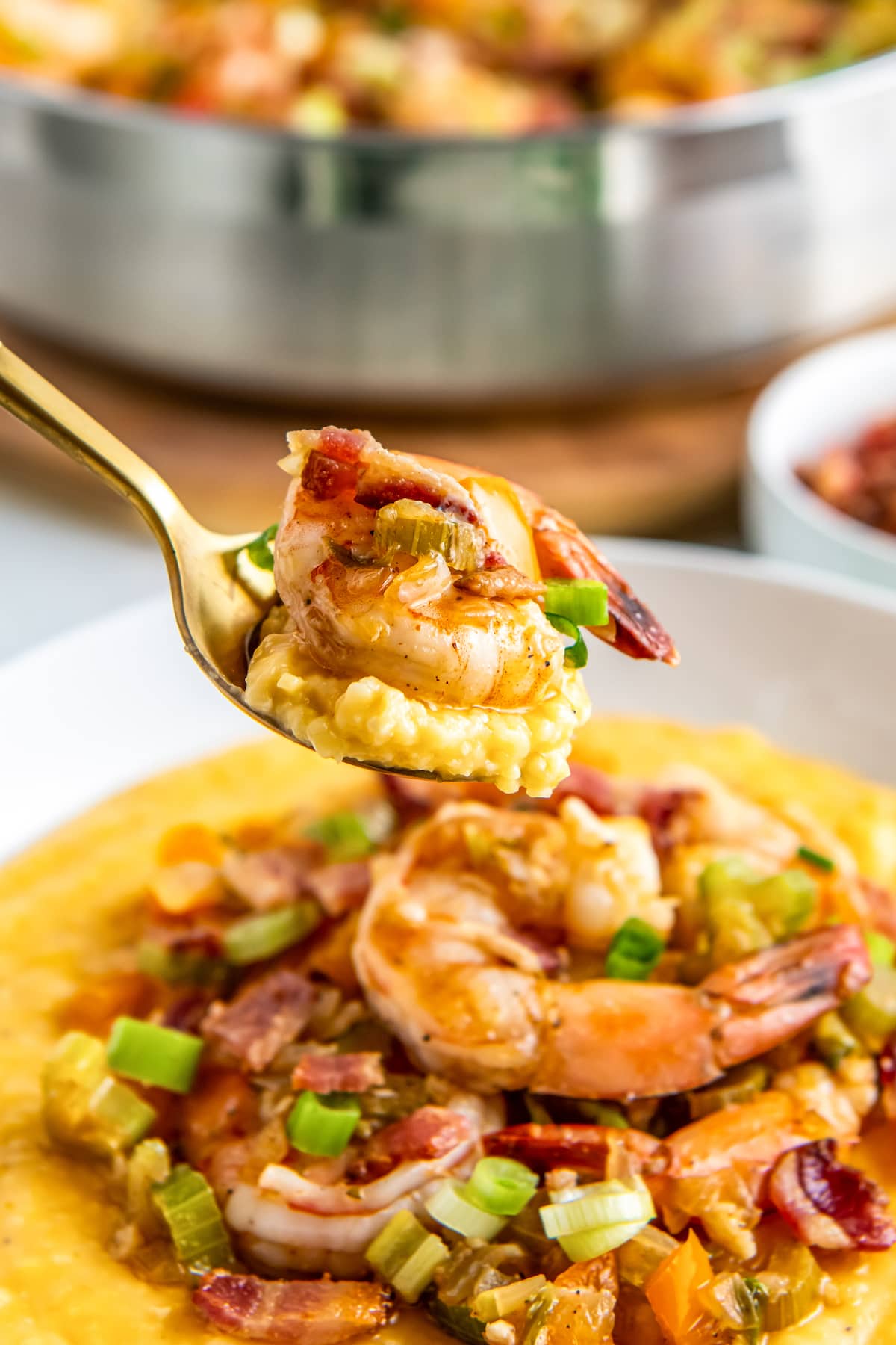 a golden spoon taking a bite of shrimp and grits