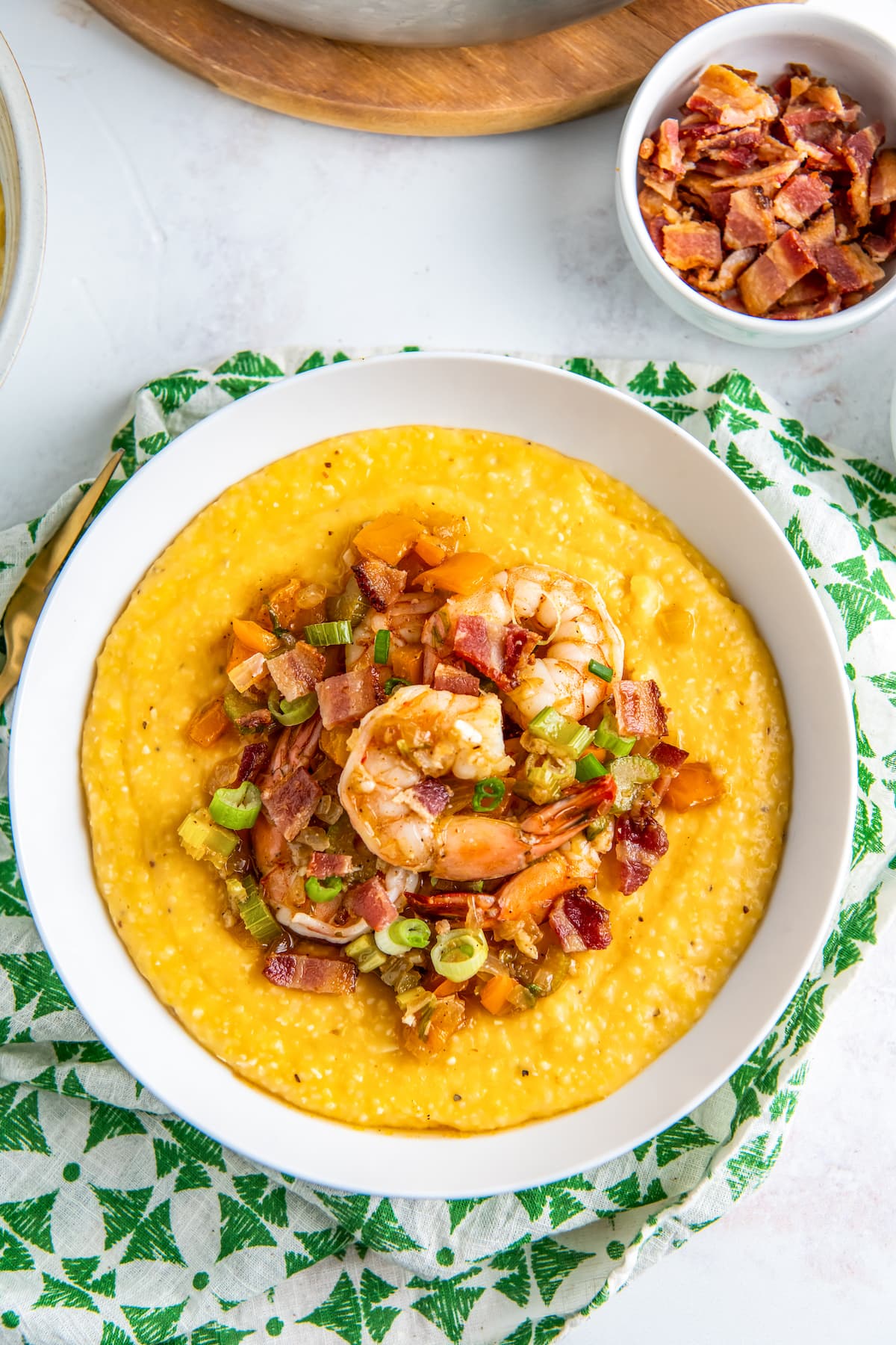 a bowl of shrimp and grits on a green and white napkin