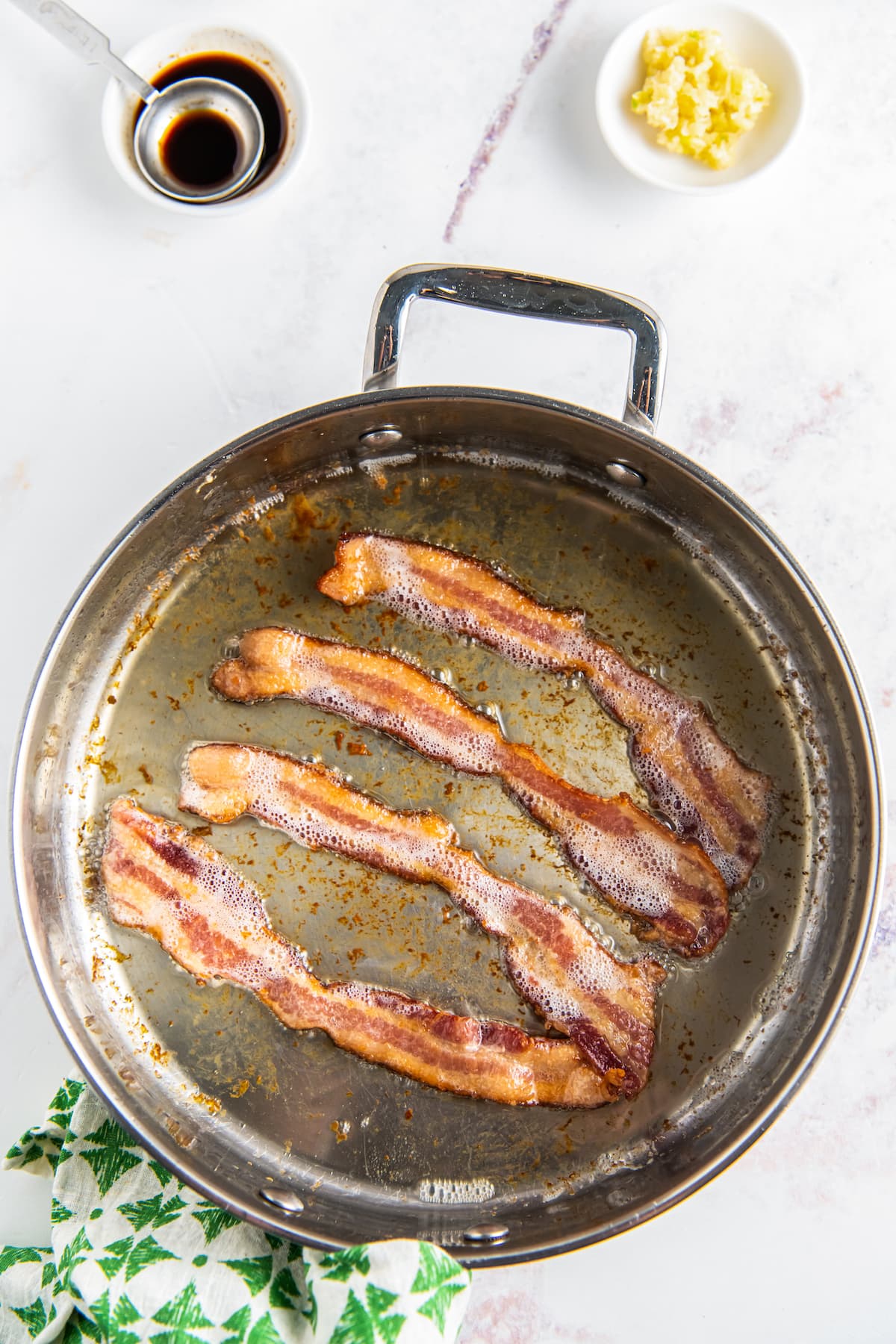 four pieces of bacon frying in a pan