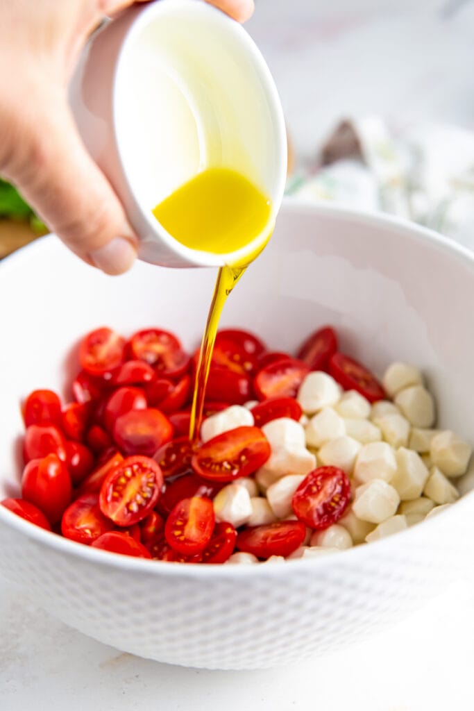Drizzling olive oil into caprese salad.
