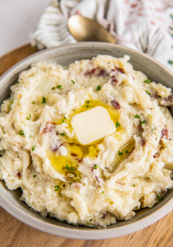 A big bowl is filled with mashed potatoes and topped with a pat of butter.