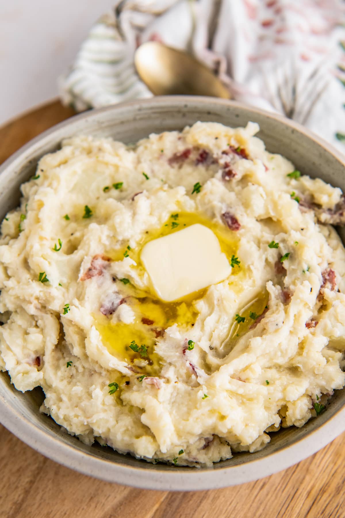 A big bowl is filled with mashed potatoes and topped with a pat of butter.