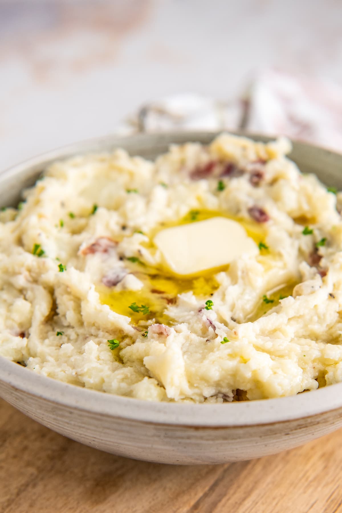 A bowl of creamy mashed potatoes is topped with a pat of melting butter.