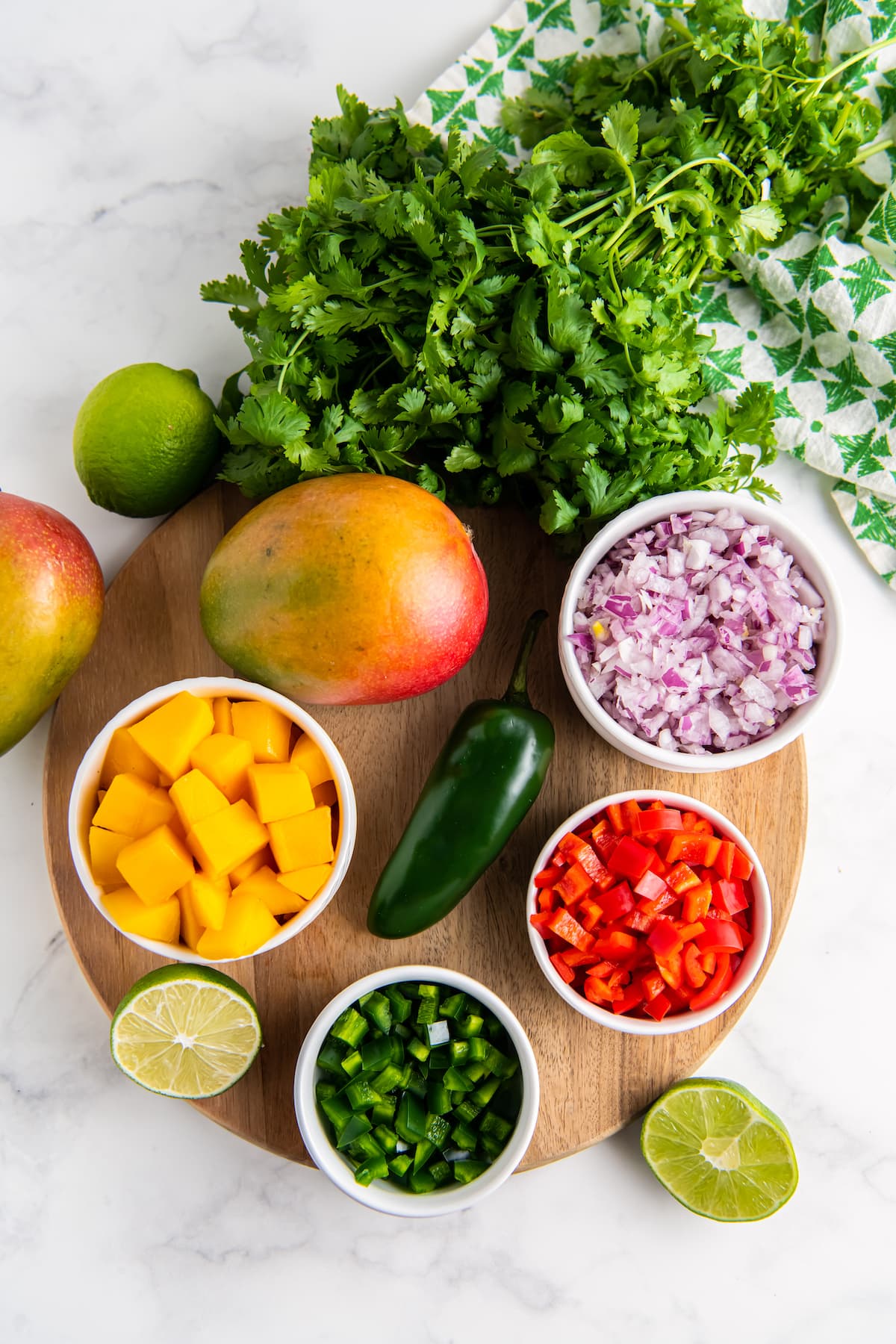 Ingredients needed to make mango salsa - mangos, cilantro, lime, bell pepper, red onion.