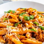 A close-up shot of One Pot Italian Sausage Pasta with cheese and basil.