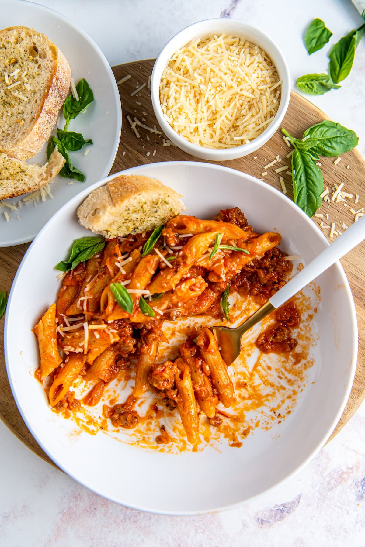 A bowl of One Pot Italian Sausage Pasta with cheese and bread is served.