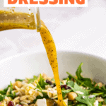 Orange dressing being poured into an orzo and arugula salad.