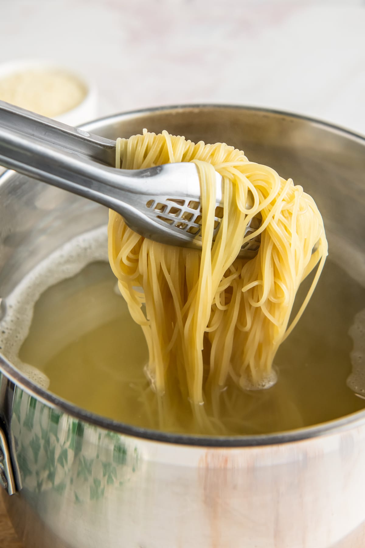 Pasta is lifted out of a pot with tongs.