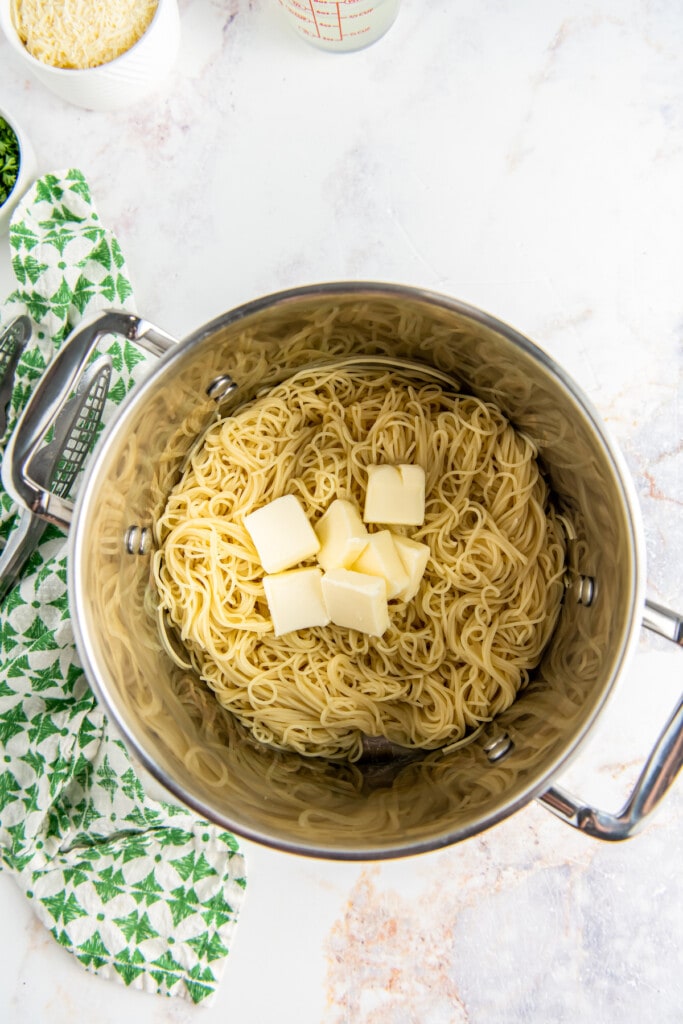 Butter is added to a pot of noodles.